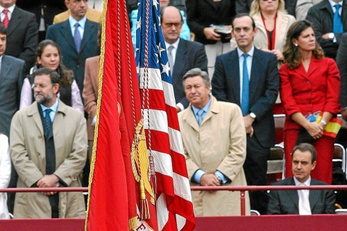 Zapatero permaneciendo sentado ante la bandera de Estados Unidos